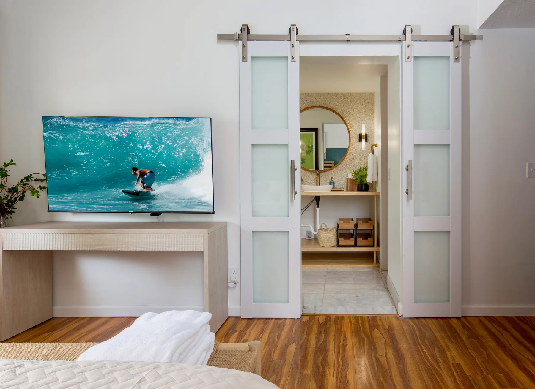 A bedroom with a television beside open sliding doors leading to a bathroom.