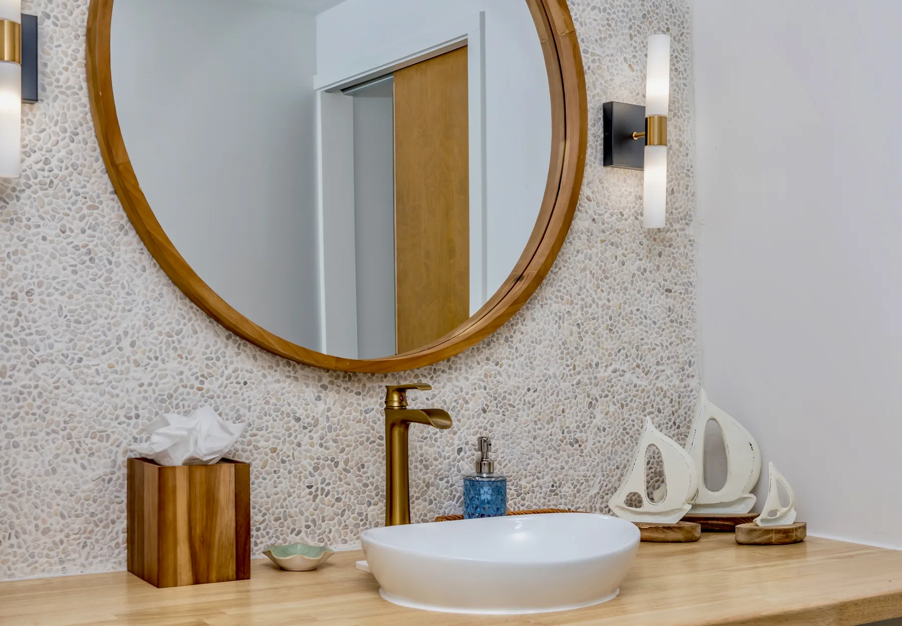 A bathroom vanity with a round vessel sink and a large circular mirror.