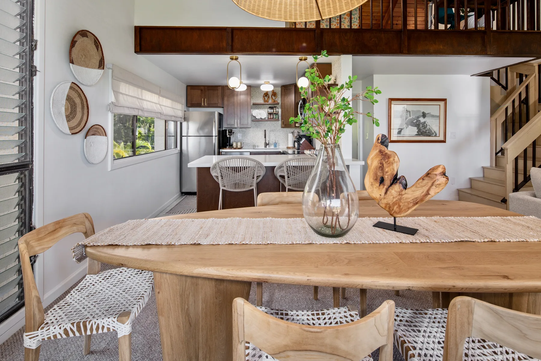 An open dining area with a wooden table and a kitchen visible behind it.