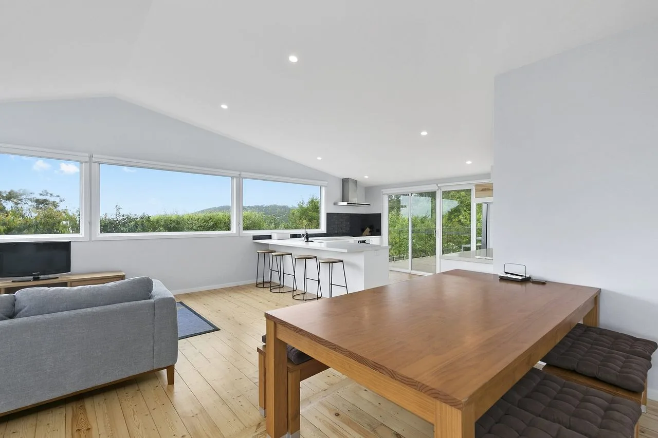 An open-plan living and dining area with a kitchen and large windows.