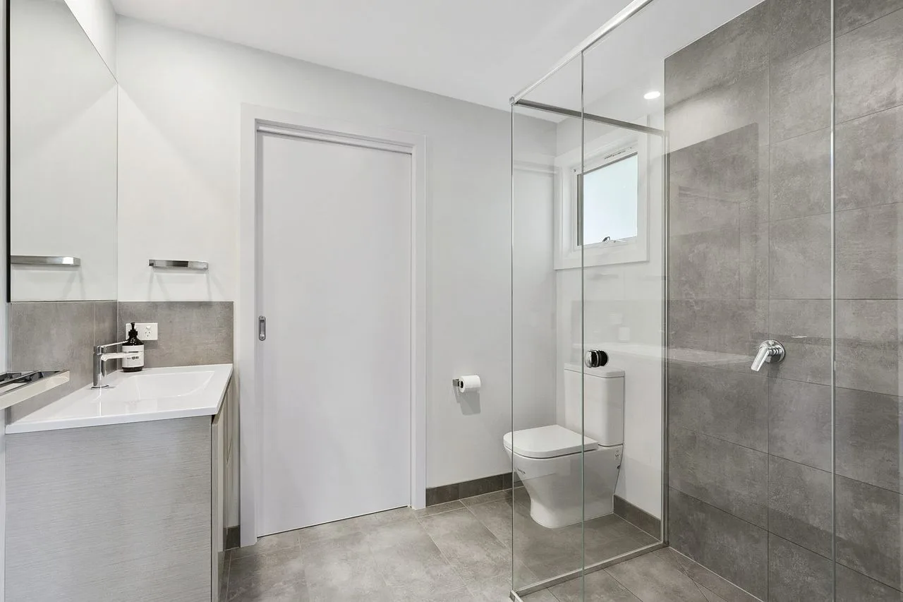 Un baño moderno con lavabo, inodoro y ducha de vidrio.