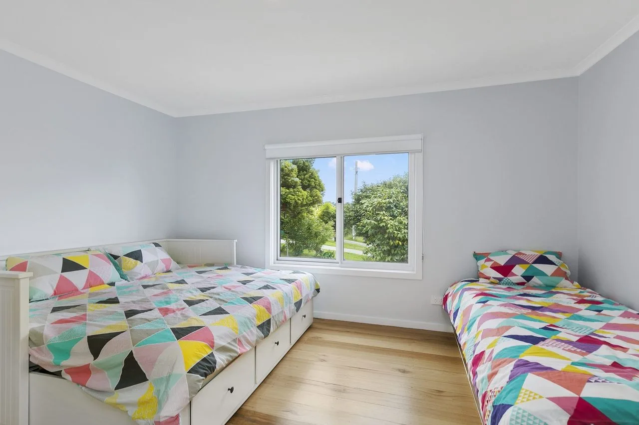 Un dormitorio con dos camas cubiertas con ropa de cama colorida de patrones geométricos.