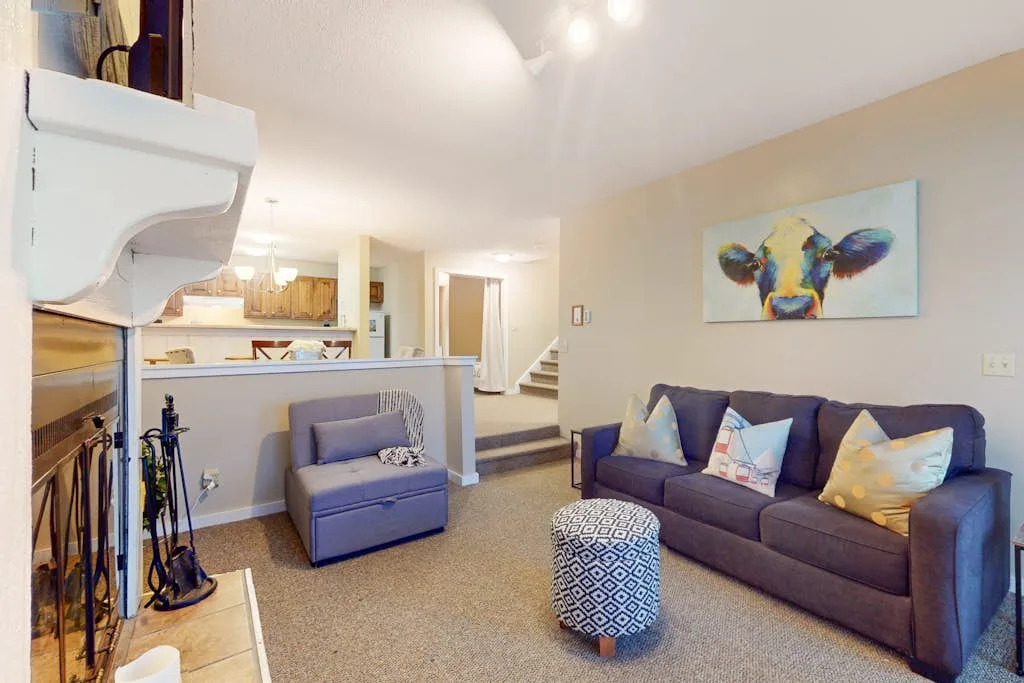 A living room with a sofa and colorful animal portrait on the wall.