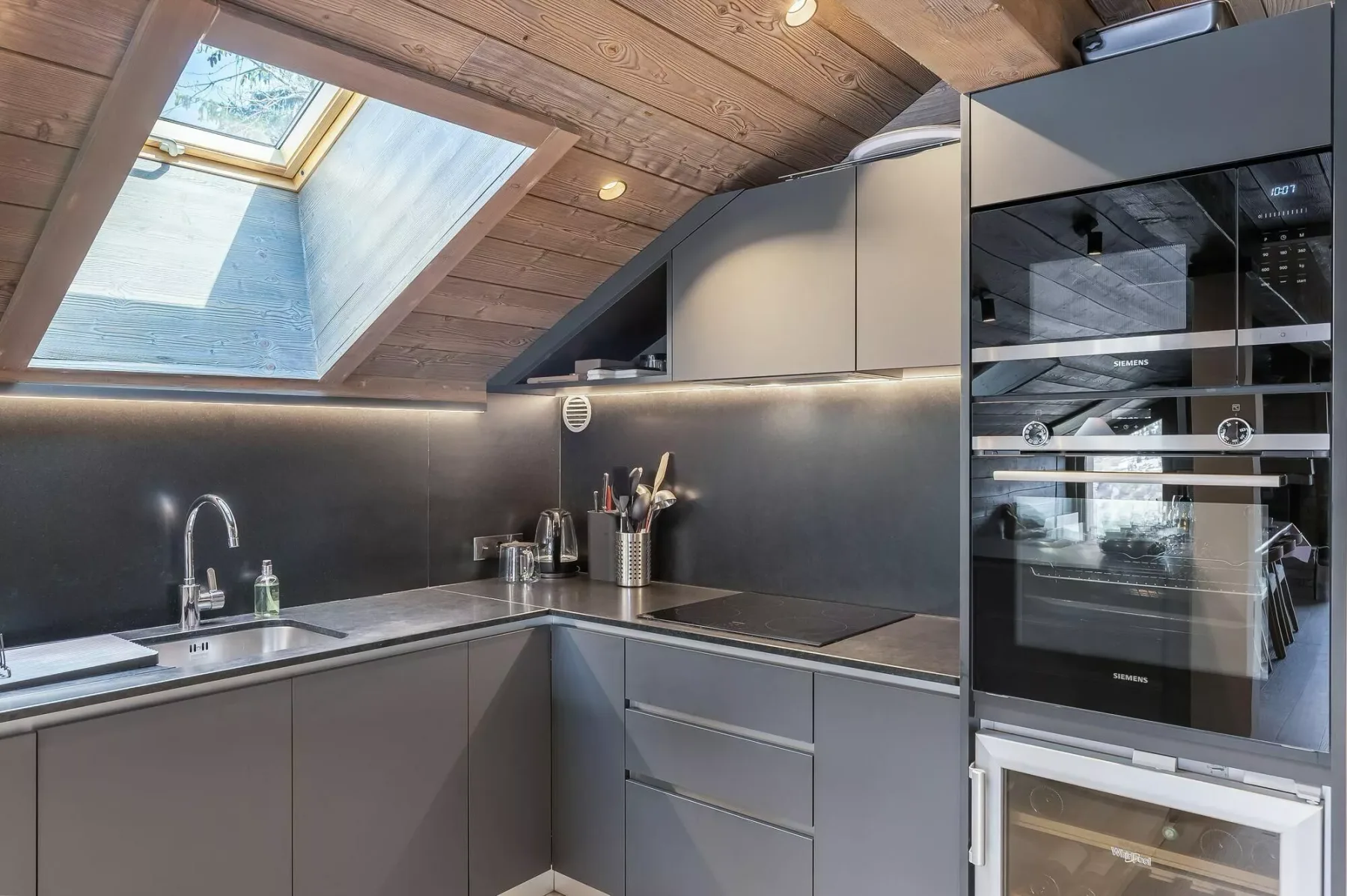 A modern kitchen with dark countertops and built-in appliances.