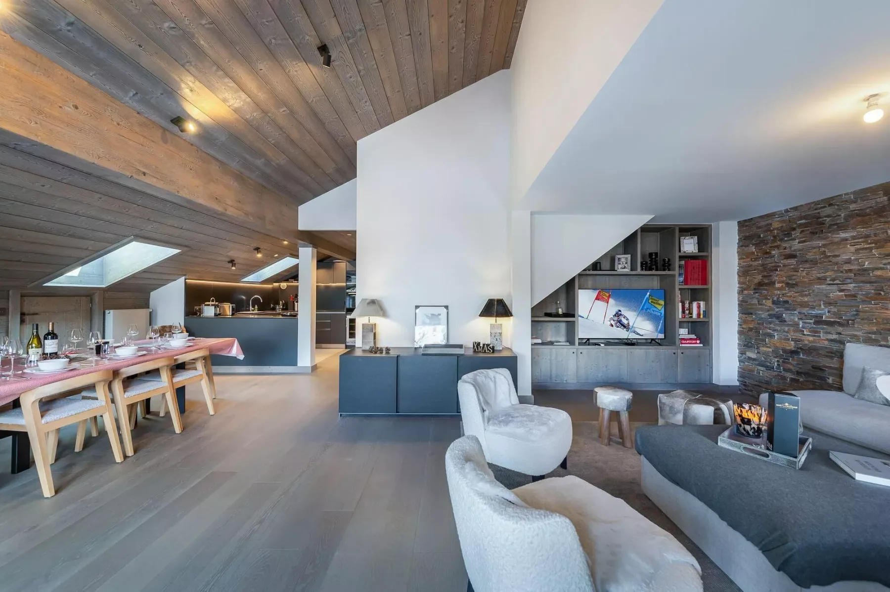 Una amplia sala-comedor diáfana con televisor y asientos.