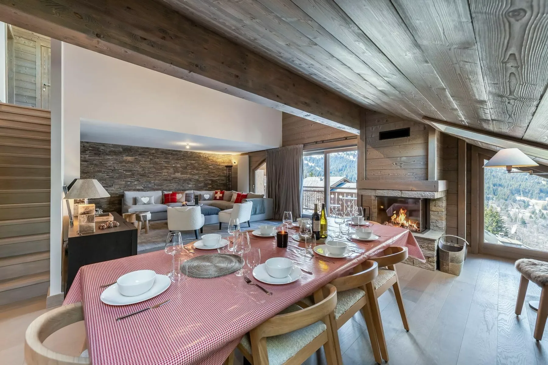 Un comedor con la mesa puesta da a una sala de estar con chimenea.