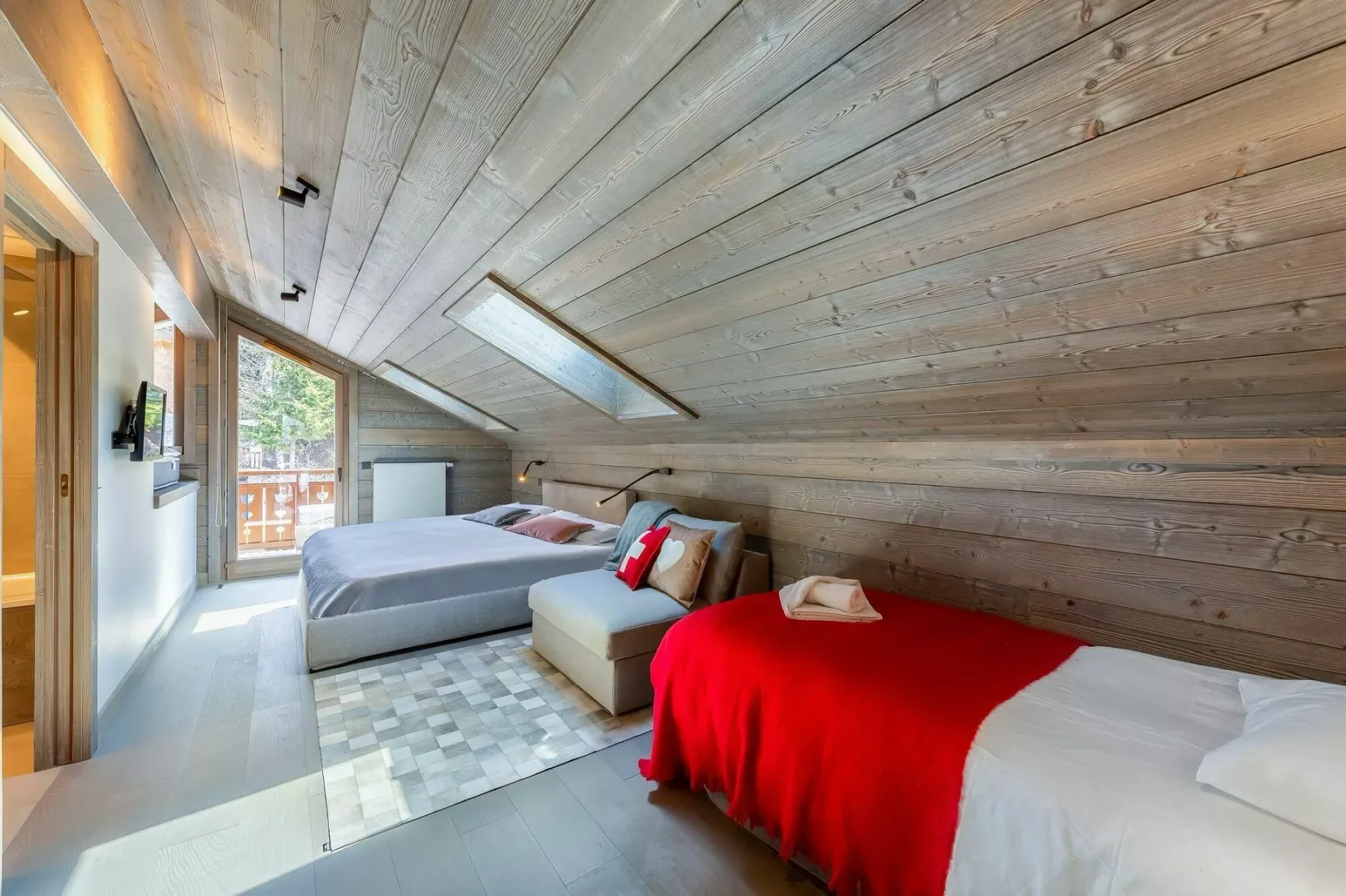 A sloped-ceiling bedroom with two beds and a skylight.