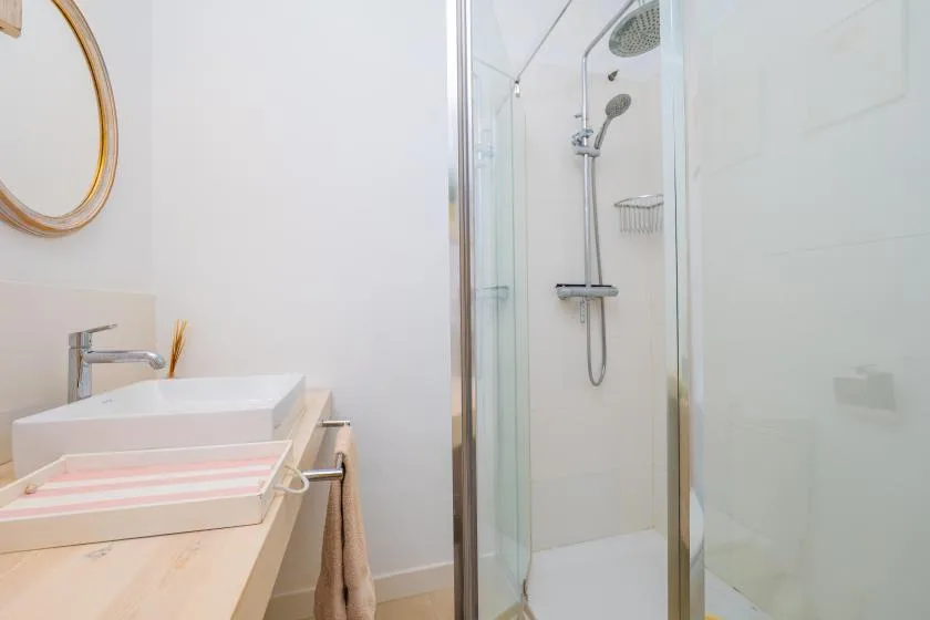 A bright bathroom with a vanity and a glass-enclosed shower.