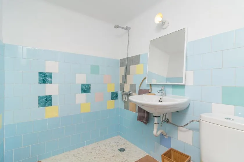 A tiled bathroom with a wall-mounted sink and shower.