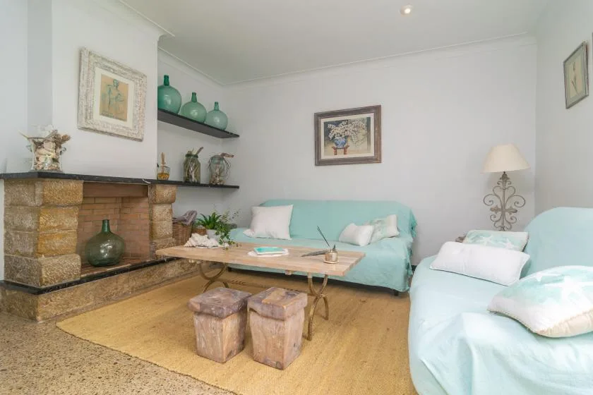 A living room with pale blue seating, a stone fireplace, and a low table.