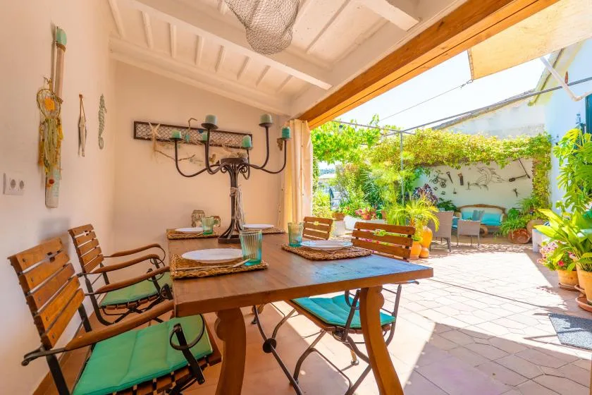 A covered patio dining area opens onto a sunny courtyard with plants and outdoor seating.