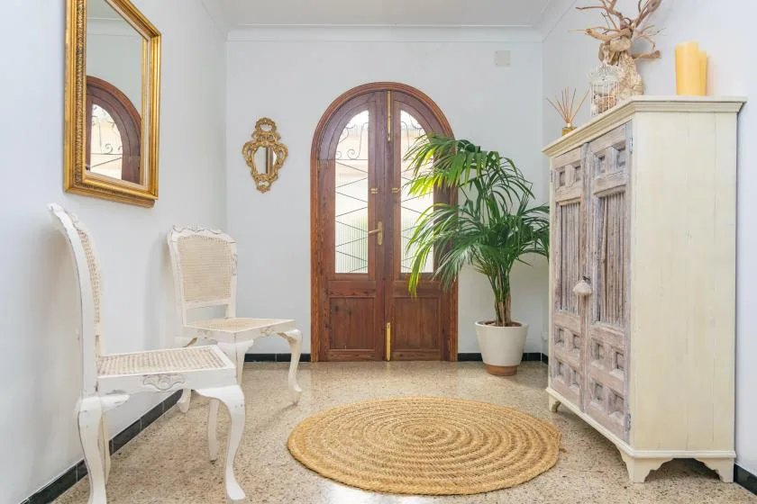 A bright entryway with an arched wooden door and a potted palm.