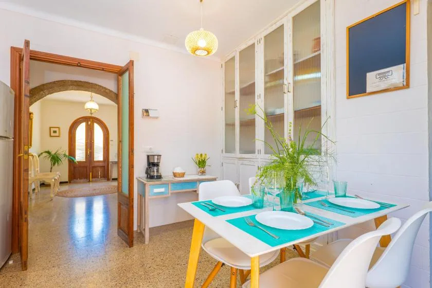A bright dining area with a set table and glass-front cabinets.