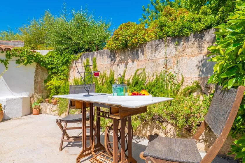 An outdoor dining area with a table and seating beside a leafy garden.