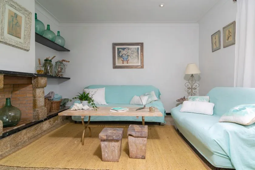 A living room with pale blue seating, a wooden coffee table, and a brick fireplace.