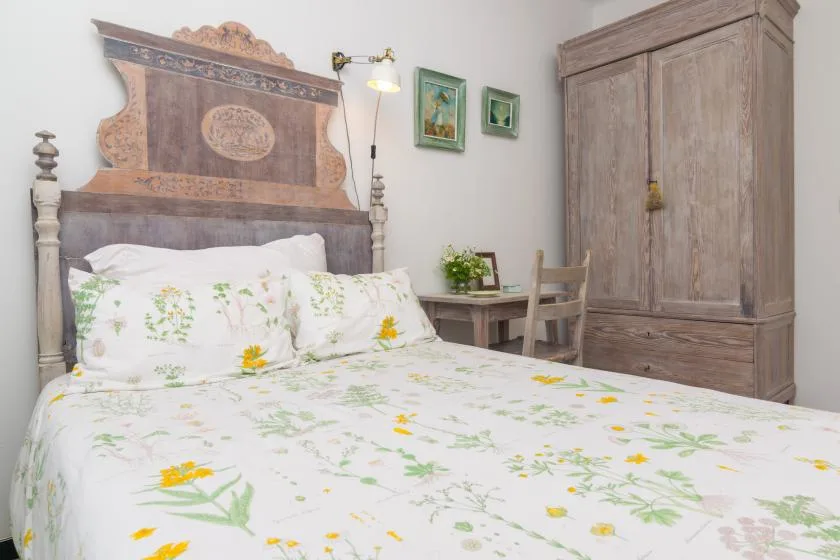 A bedroom with a floral bedspread and a wooden wardrobe.