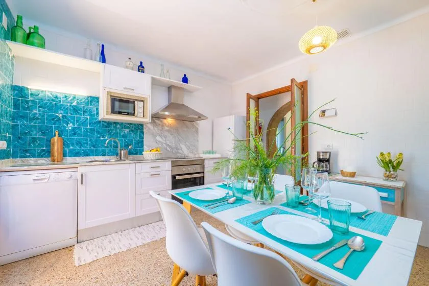 A bright kitchen and dining area with turquoise tile and a set dining table.