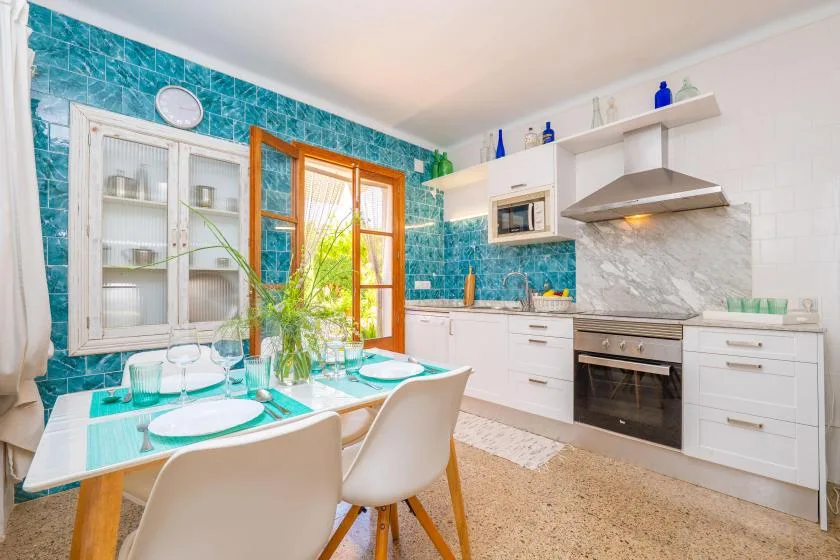 A bright kitchen and dining area with turquoise tile and a table set for a meal.