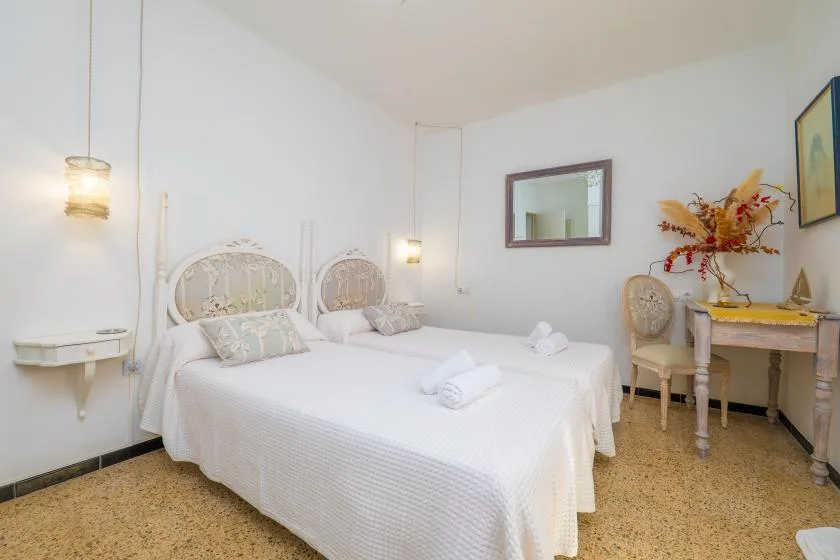 A bright bedroom with two beds dressed in white linens.