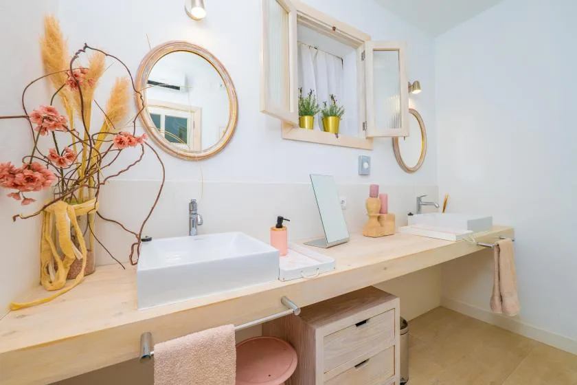 A bright bathroom vanity with a vessel sink, mirror, and flowers.