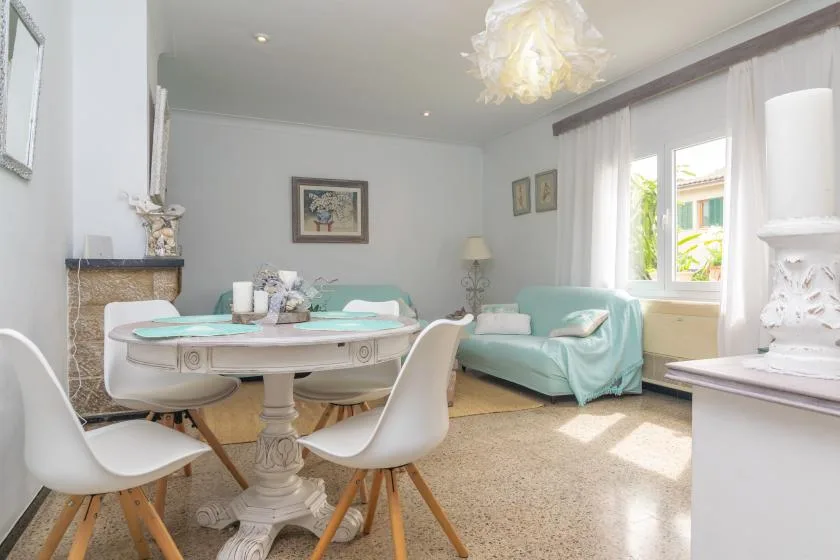 A bright sitting room with a round dining table and seating beside the windows.
