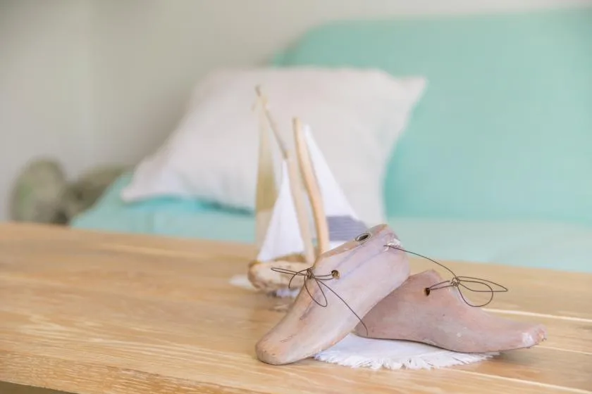 A small sailboat model rests on a wooden table in front of a bed.