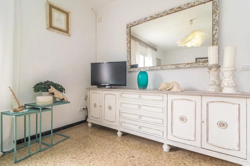 A bright living room features a white sideboard beneath a large mirror.