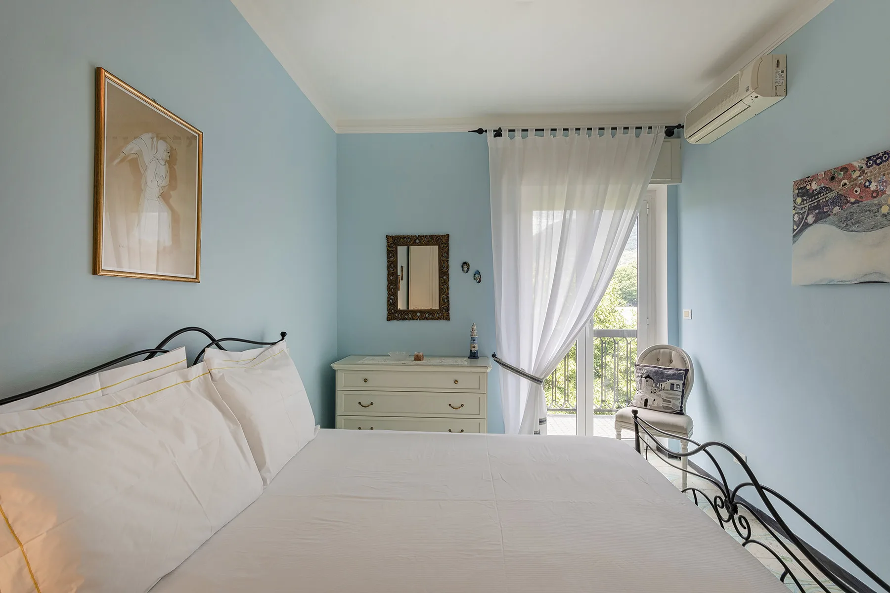 Un dormitorio con una cama tendida junto a una ventana luminosa.