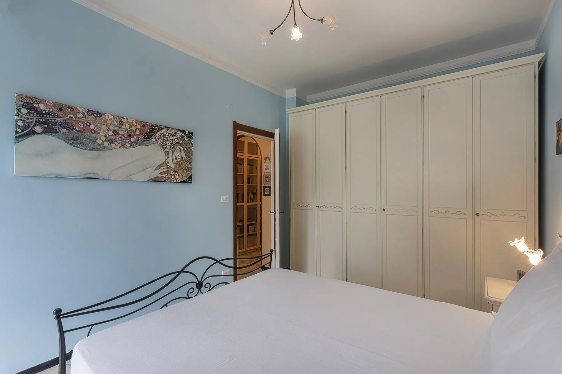Un dormitorio con una cama grande, armarios blancos y paredes azules.