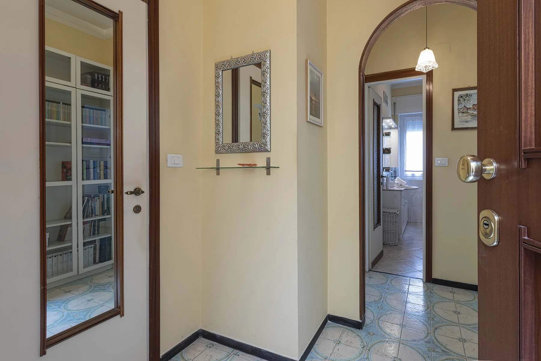 Un pasillo interior con suelo de baldosas estampadas y varias puertas.