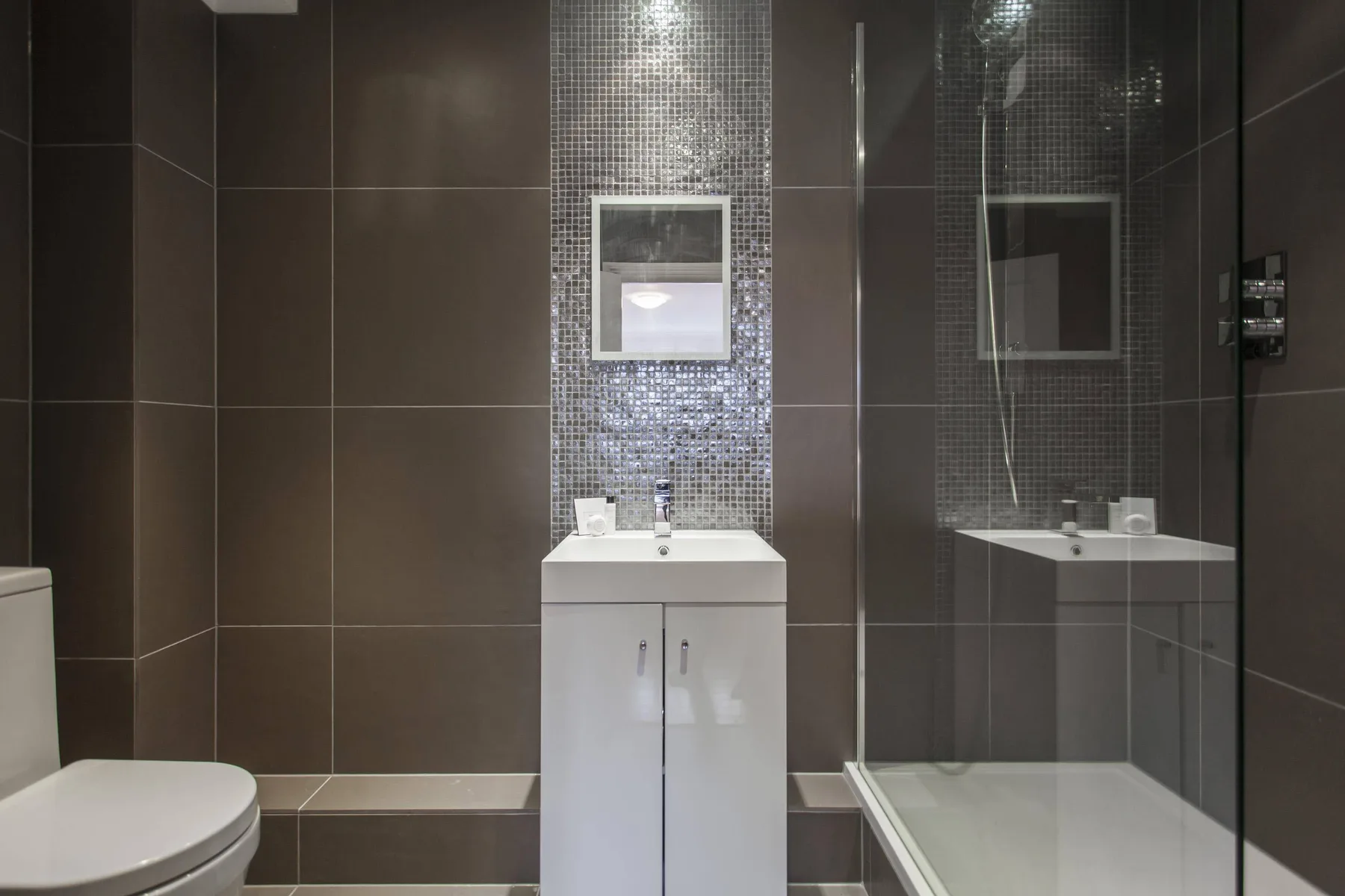 Un baño moderno con un lavabo blanco y una ducha con mampara de vidrio.
