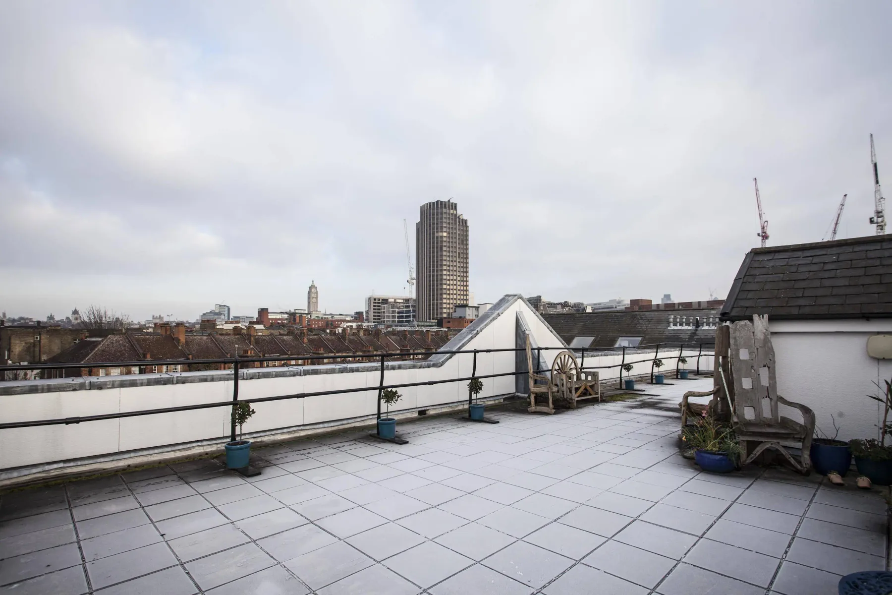 Una terraza en la azotea con suelo de baldosas y vistas a la ciudad.