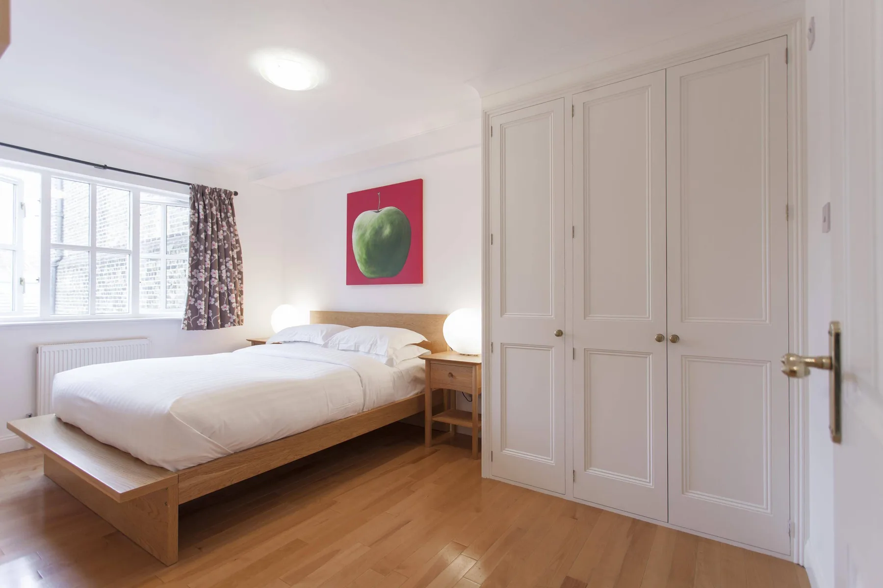 Un dormitorio luminoso con una cama, una ventana y armarios empotrados.