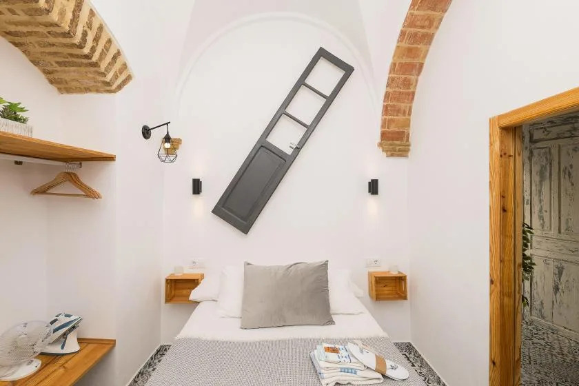 A bright bedroom with a bed beneath a decorative ladder-shaped wall feature.
