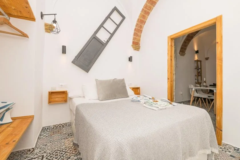A bedroom with a neatly made bed and patterned tile flooring.