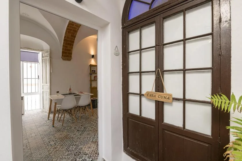 Una puerta oscura de paneles de vidrio da a un comedor con suelo de baldosas estampadas.