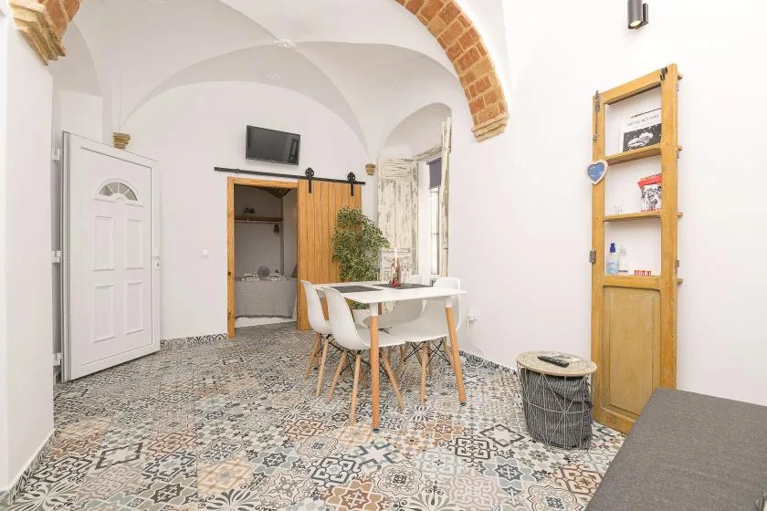 A bright dining area with a table and chairs beneath a brick arch.