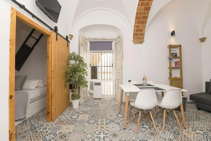 A dining area with a table and chairs beside an open sleeping area.