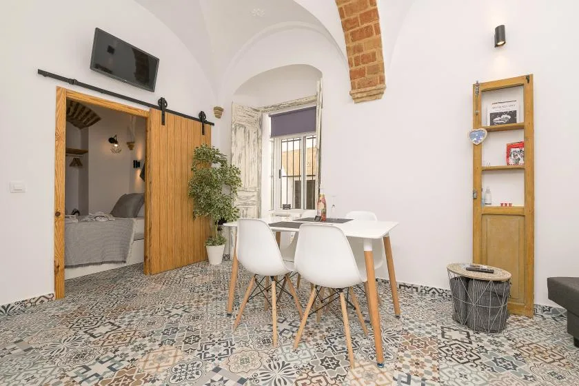 A bright dining area with a white table and chairs beside a bedroom doorway.