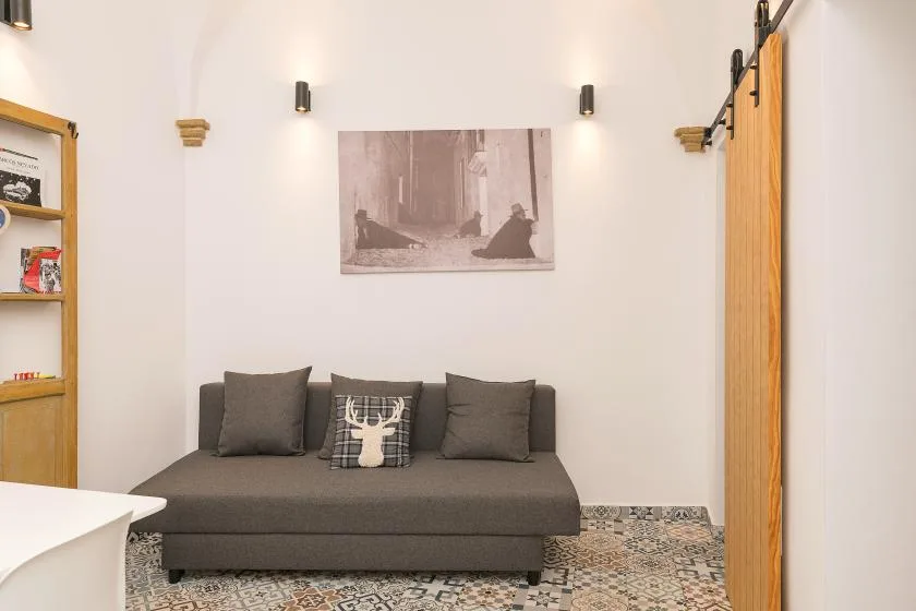 Una sala de estar con asientos oscuros bajo una lámina enmarcada.
