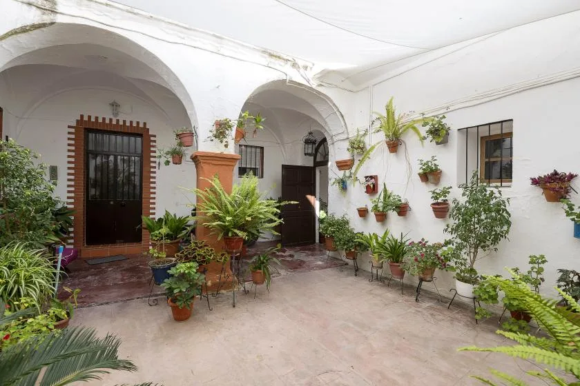 A courtyard with arched doorways and potted plants along the walls.