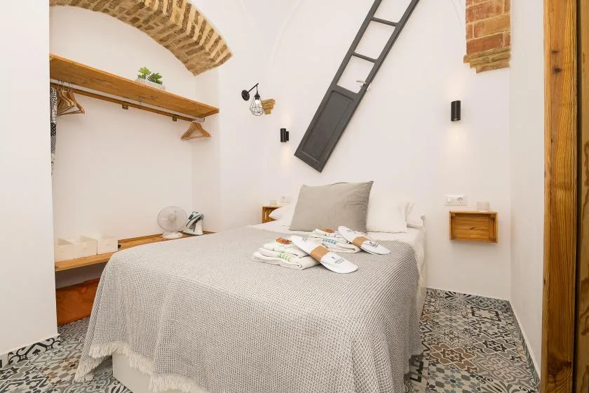 A bedroom with a neatly made bed and patterned tile flooring.