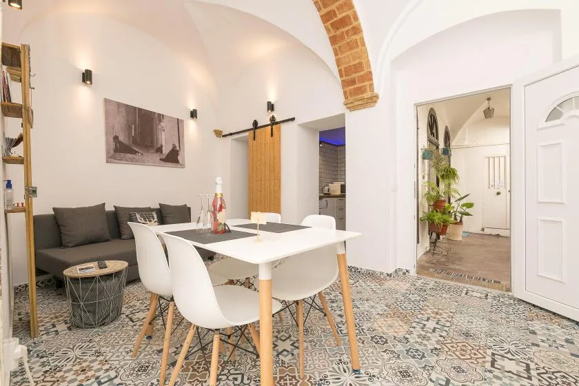 A bright dining area with a white table, chairs, and an adjoining sitting area.