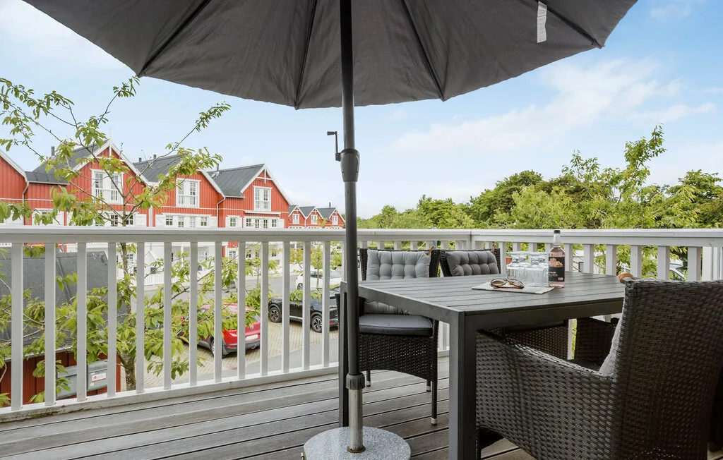 Una terraza exterior con una mesa de comedor y asientos bajo una sombrilla grande.