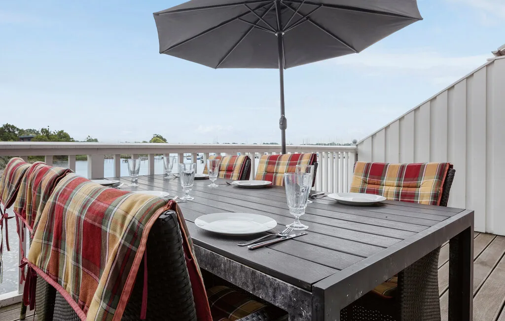 Comedor en una terraza con mesa, asientos coloridos y una sombrilla grande.