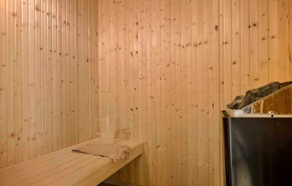 Una sauna revestida de madera con un banco y un calentador lleno de piedras.