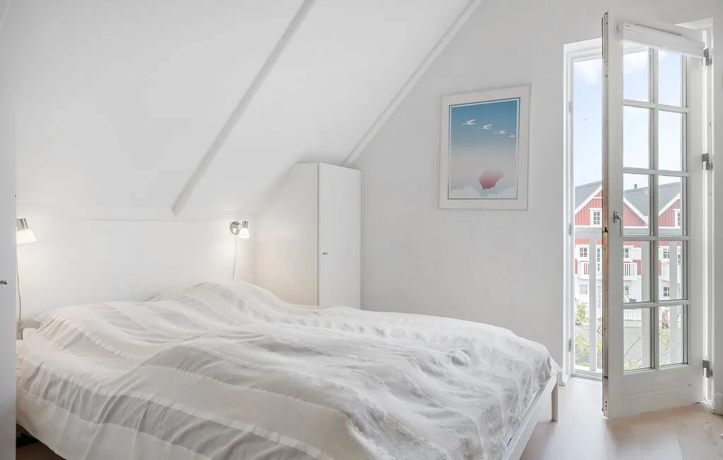 Un dormitorio abuhardillado luminoso con una cama y una ventana abierta.