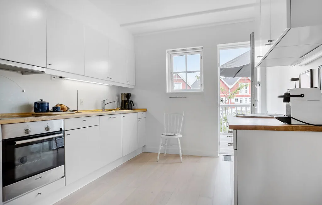 Una cocina luminosa con gabinetes blancos, una encimera y una silla.