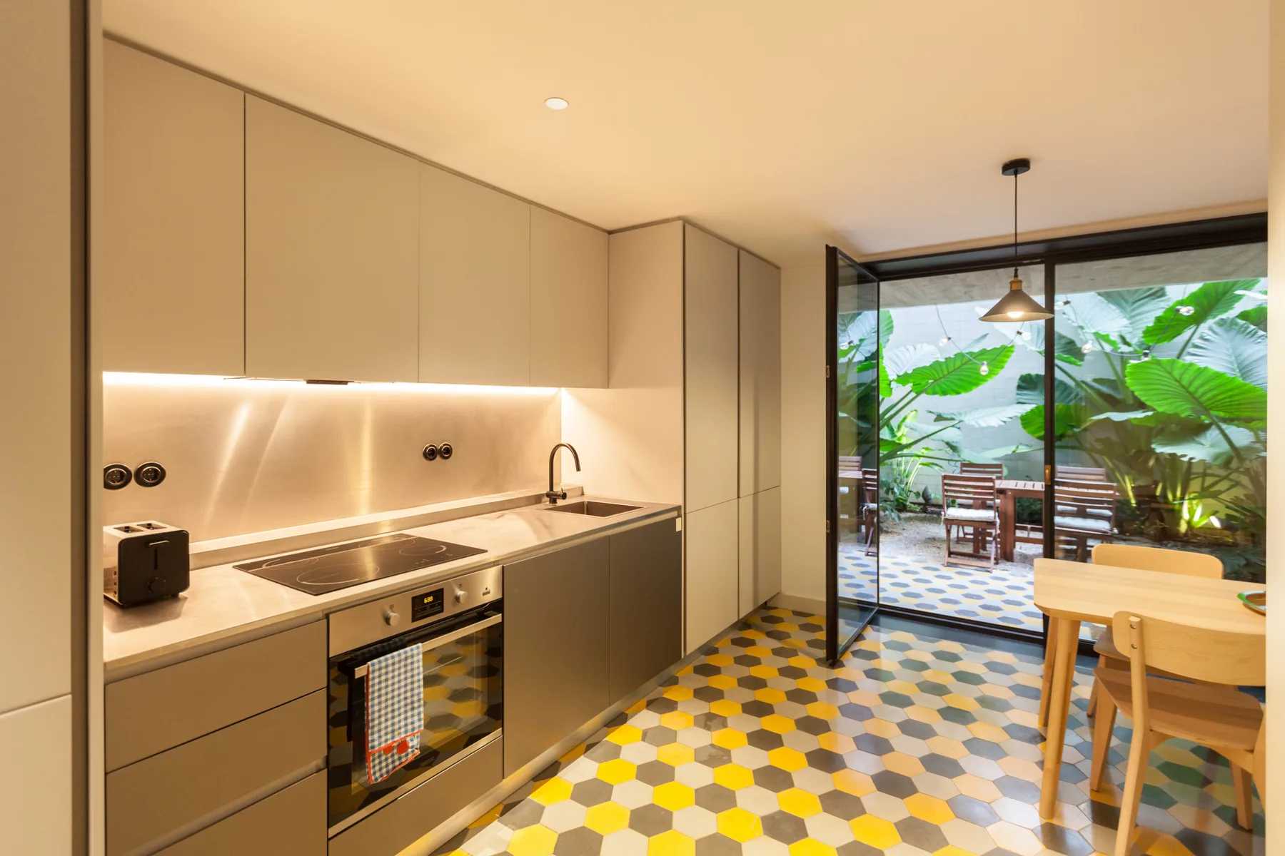 Una cocina moderna se abre a un comedor y un patio frondoso.