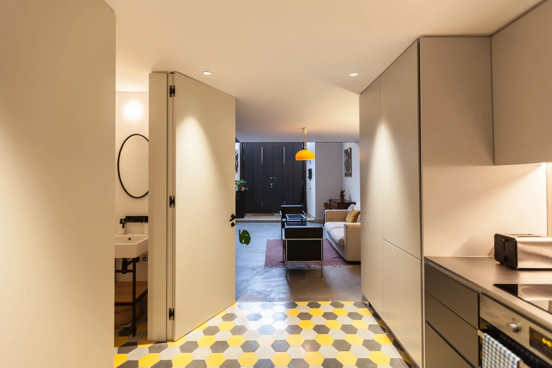Interior de apartamento con una cocina en primer plano y una sala de estar al fondo.